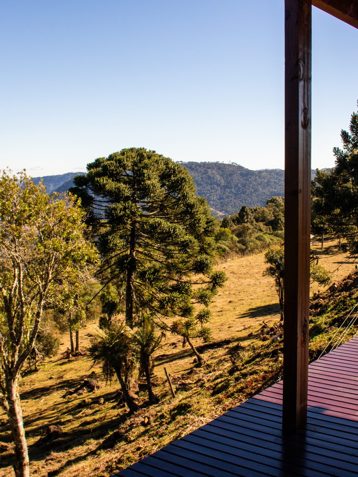 Varanda da pousada com vista para o jardim e as montanhas ao amanhecer